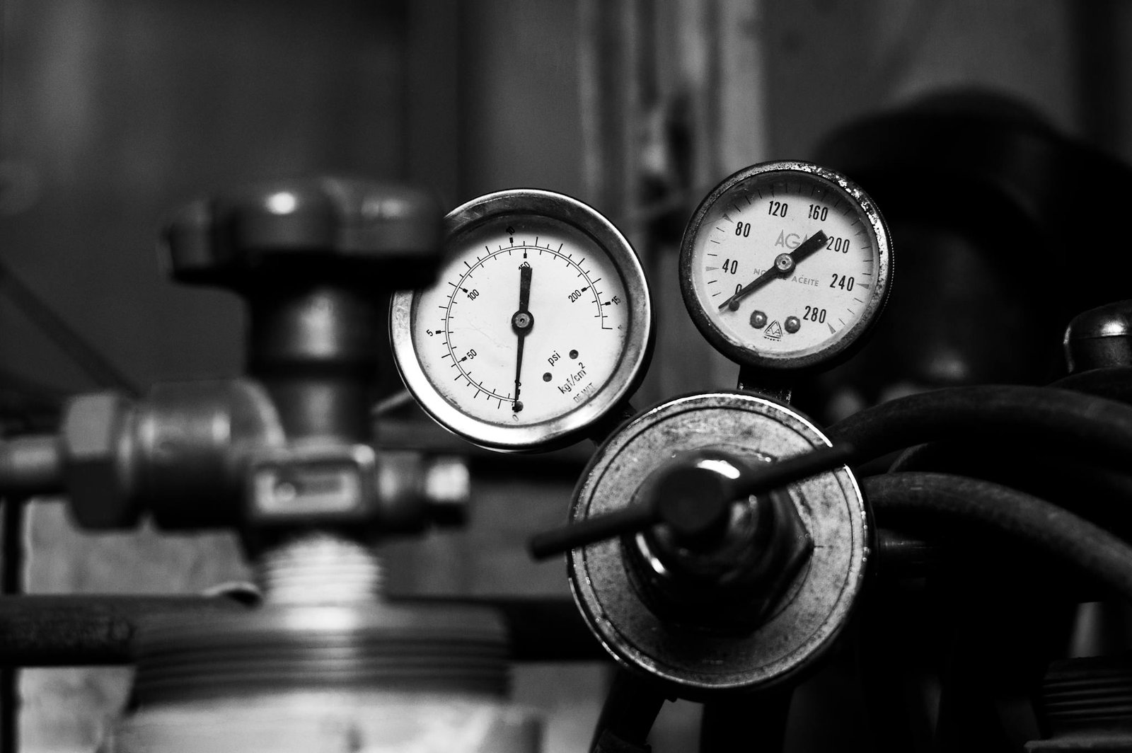 A detailed monochrome image of vintage industrial pressure gauges with metal pipes.